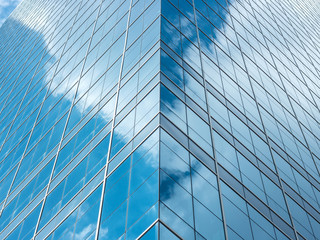 Perspective and underside angle view to textured background of modern glass building skyscrapers over blue cloudy sky
