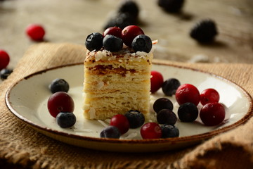Piece of cake napoleon on a plate with sweet fresh berries