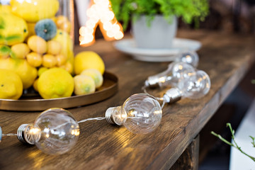 Elements of decor for home and garden. Yellow lemons in a jar. Rare incandescent lamps. Live flowers in a pot. Design and style.