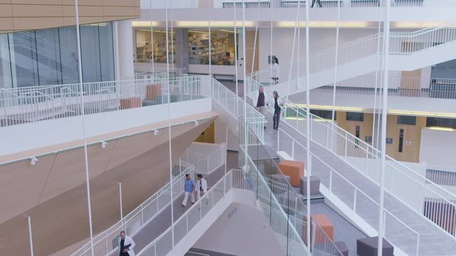 High Angle Handheld Shot Of Coworkers Walking In Hospital Corridor