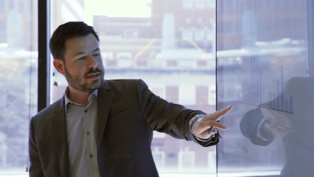 Handheld shot of businessman explaining graph in meeting at board room