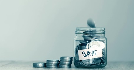 A  money coins falling into  glass jar with label of SAVE text , business and financial of  money saving concept , 4K Dci resolution - Powered by Adobe