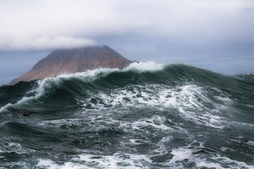 high storm surge of the Pacific Ocean on the background of the Kuril Islands with rainbow
