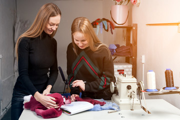 Two young women furriers are discussing how to properly cut natural fur to make a woman's fur coat. The process of making a woman's fur coat