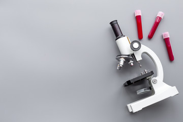 Do blood test in laboratory. Analysis. Blood samples in test tubes near microscope on grey background top view copy space