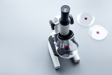 Do blood test in laboratory. Analysis. Samples in petri dish near microscope on grey background top view copy space