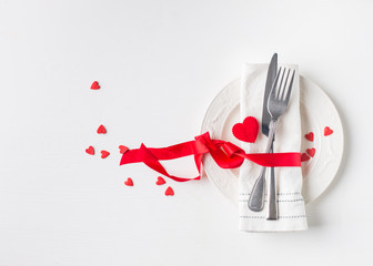 Valentines day (or wedding) meal background with red ribbon, hearts, fork, knife, white plate and...