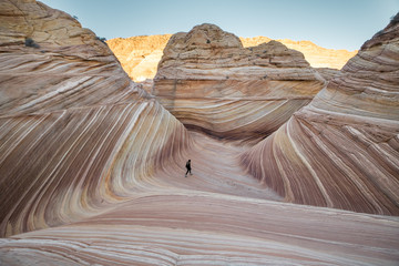 The Wave, AZ at Sunrise with Soft lighting. Girl hiking through beautiful unique rock formation 