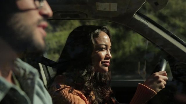 Handheld shot of woman talking to man in car