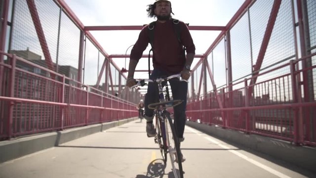 Young man riding bicycle on bridge during summer