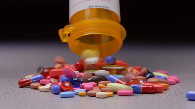A prescription pill bottle spilling out an assortment of pills