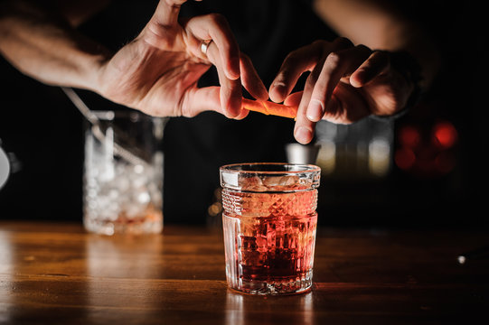 barman preparing alcoholic cocktail negroni of pink color with ice