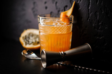 alcoholic cocktail of orange color with ice and citrus stands on a black background