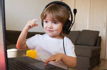 little child with headphones playing computer