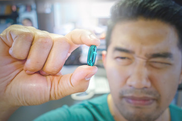 Men holding a translucent green pills in hand