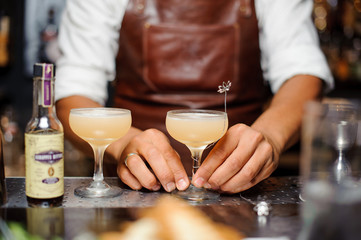 barman decorates with a wire crystal wine glasses with alcoholic cocktails