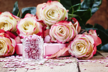 Obraz na płótnie Canvas Pink sugar hearts, Valentines card on background of fresh roses, selective focus