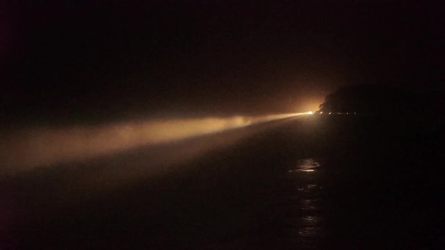 Lockdown shot of illuminated lighthouse by sea against sky at night