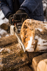 Man cuts firewood in chainsaw in winter