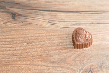 A single chocolate displayed on a wooden background