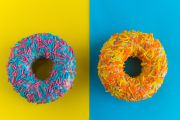 top view colorful donuts on yellow and blue background