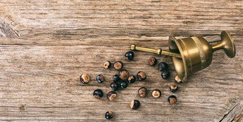 Guarana nuts and a metal mortar on wooden background, top view, copy space