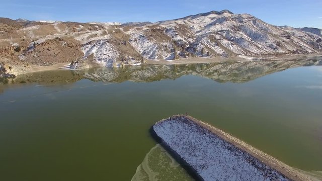 Aerial view flying over rocky point on Piute Reservoir with person standing on the end in Utah.