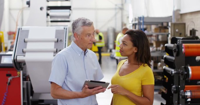 4k, Workers  discuss business with digital tablet standing on the factory floor. Slow motion.