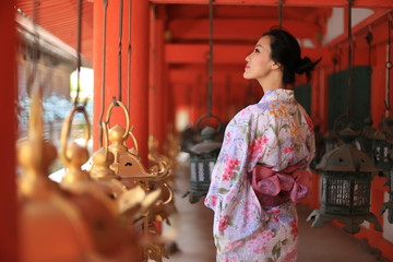 a young Japanese woman in summer kimomo (yukata) with traditional lanterns in a traditional...