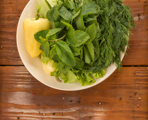 Green pepper with green salad, apple and basil on the plate placed on the rustic vintage wooden background