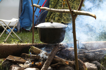 The pot hangs over the fire. Cooked meals in open air. Cooking food in nature. Tourist dinner.