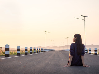 Young asian woman sitting on the road at sunrise