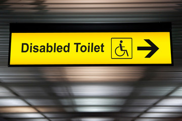 sign with arrow point to disabled toilet at the airport for passenger with impaired body. universal design for elderly or the disabled in public place concept.