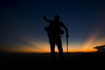 Silhouette of man hiking on top mountain trees forest with light during sunset, winter season