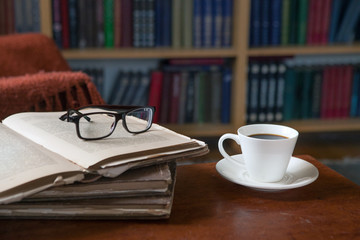 Sweet moments of relaxation with books and a cup of coffee. Vintage books, glasses, chair, library