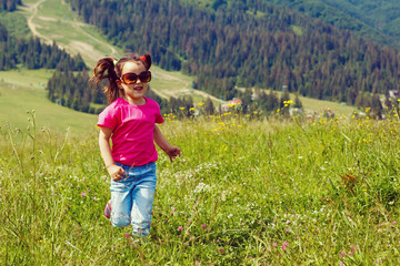 funny little happy girl on the mountain top. Freedom, little girl playing on meadow. Travel, lifestyle concept