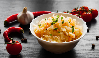 pickled cabbage and carrots in a white bowl on dark wooden background