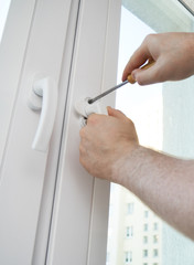 Professional handyman fixing window handle at home.