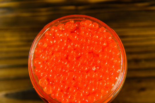 Red caviar in glass jar on wooden table. Top view