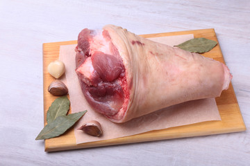 Raw pork knuckle, Aromatic dried bay leaves, garlic and spices on a cutting board. Selective focus. Ready for cooking.