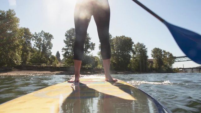 Handheld shot of woman paddleboarding in river against sky