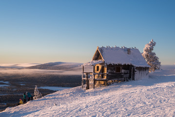 Old abandoned cottage and skiers at the mountain Levi lapland
