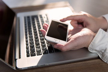 ノートパソコン・スマートフォンを操作する男性