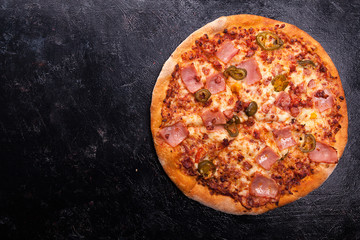 Top view of fresh baked hot pizza on dark wooden background with copy space available