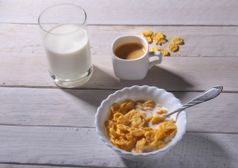 Corn Flakes cereal in a bowl, glass with milk and cap with espresso coffee. Morning breakfast.