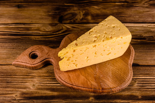 Cutting board with piece of cheese on a wooden table