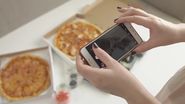Photographing food. Hands of girl with smartphone taking picture of delicious pizza