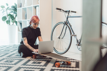 young businesswoman in eyeglasses using laptop on skateboard - Powered by Adobe