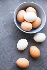 Baking Homemade Pastry Concept. Chicken eggs in a bowl and on the table, dark concrete as background, top view