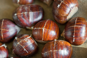 Chestnuts being prepared for baking with a knife-cut cross on top of each nut